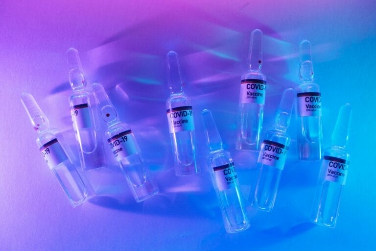 From above set of COVID 19 vaccines placed on table in modern laboratory with bright neon lights